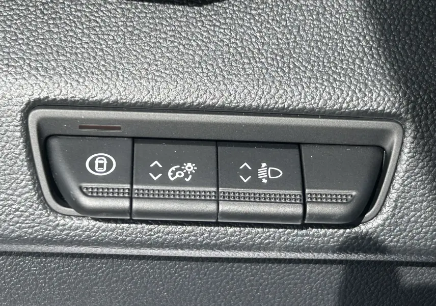 Boutons de réglage de luminosité et hauteur des phares sur tableau de bord noir du Renault Trafic Fourgon blanc.