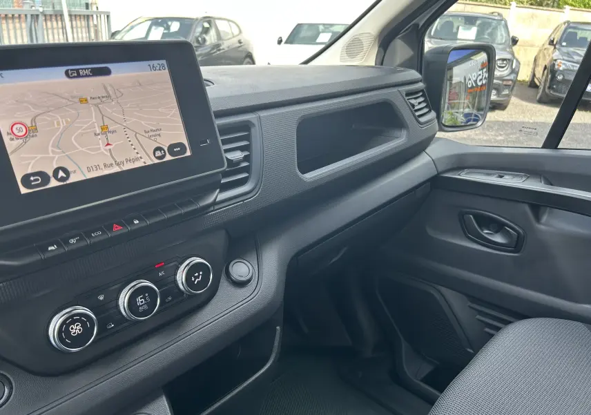 Vue intérieure côté passager du Renault Trafic Fourgon L1H1 2026, montrant la console centrale avec écran tactile et commandes de climatisation.