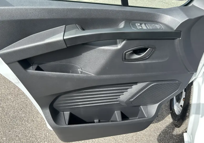 Vue rapprochée de la porte avant droite blanche du Renault Trafic Fourgon avec commandes de vitres et haut-parleur intégré.