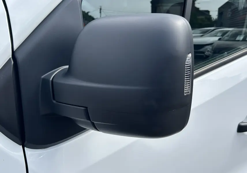 Gros plan sur le rétroviseur noir côté gauche du Renault Trafic Fourgon blanc, avec clignotant intégré.
