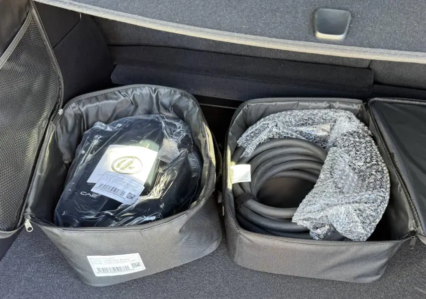 Vue du coffre du BYD SEAL U 2026 avec deux sacs noirs contenant des câbles de recharge.