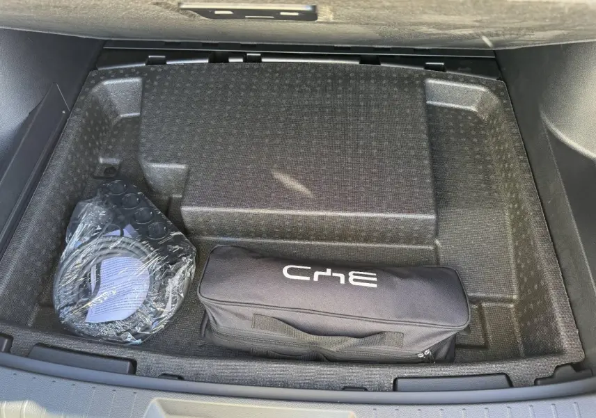 Vue plongeante sur le coffre ouvert du BYD SEAL U 1.5 DM-i 324ch Design AWD noir, montrant un rangement avec sac et câble.