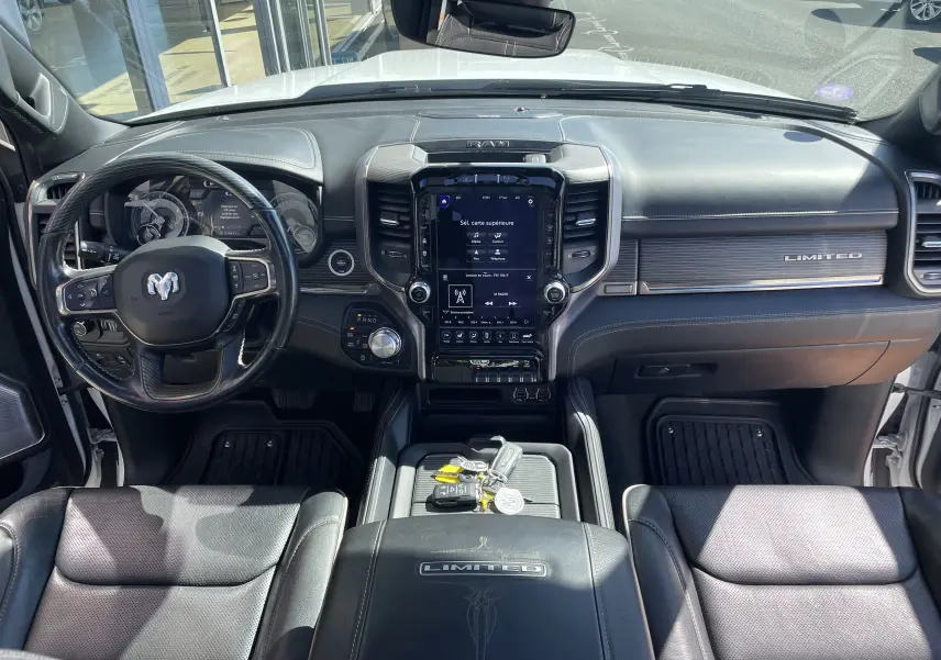 Vue intérieure frontale du Dodge RAM 1500 Limited 2020 avec tableau de bord noir, écran tactile central et volant cuir noir.