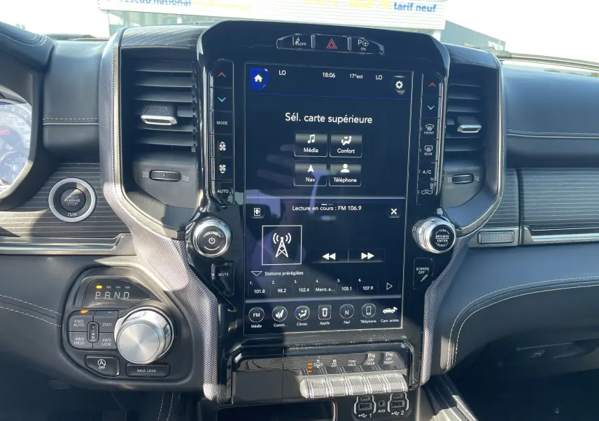 Tableau de bord du Dodge RAM 1500 blanc nacré, vue centrée sur l'écran tactile et commandes de la console centrale.