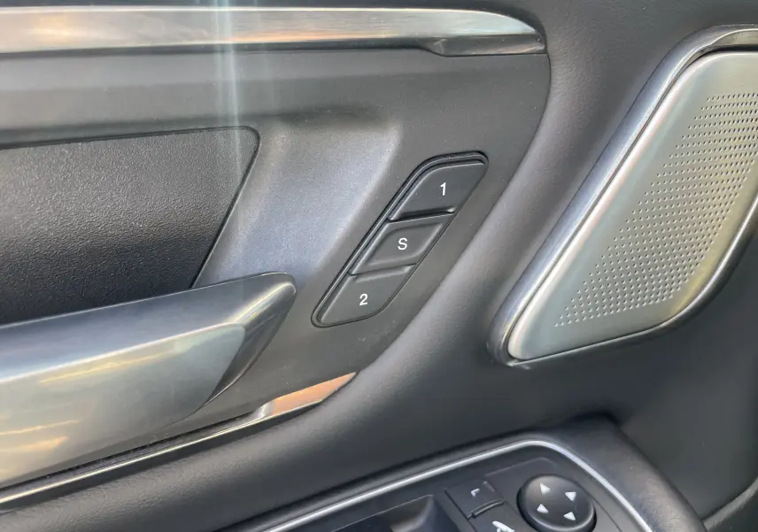 Gros plan sur la porte côté gauche du Dodge RAM 1500 blanc nacré, montrant les commandes mémoire sièges et haut-parleur intégré.