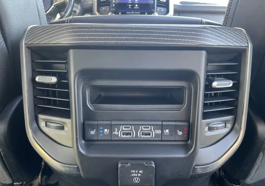 Gros plan sur la console arrière noire du Dodge RAM 1500 2020, avec commandes de sièges chauffants et ventilés, prises USB et prises d'air.