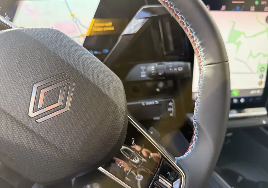 Gros plan sur le volant cuir du Renault Austral 2025 avec commandes intégrées et écran de navigation en arrière-plan.