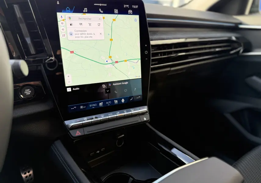 Vue intérieure du tableau de bord du Renault Austral 2025, écran tactile central avec navigation et commandes climatiques visibles.