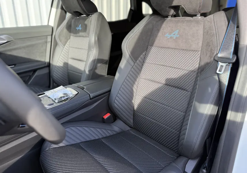 Gros plan sur les sièges avant en cuir et alcantara gris foncé avec logo Alpine bleu, intérieur Renault Austral 2025.