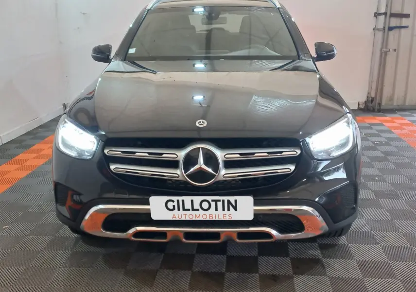 Vue frontale d'un Mercedes GLC 300 E Business Line hybride noir avec phares LED allumés en intérieur.