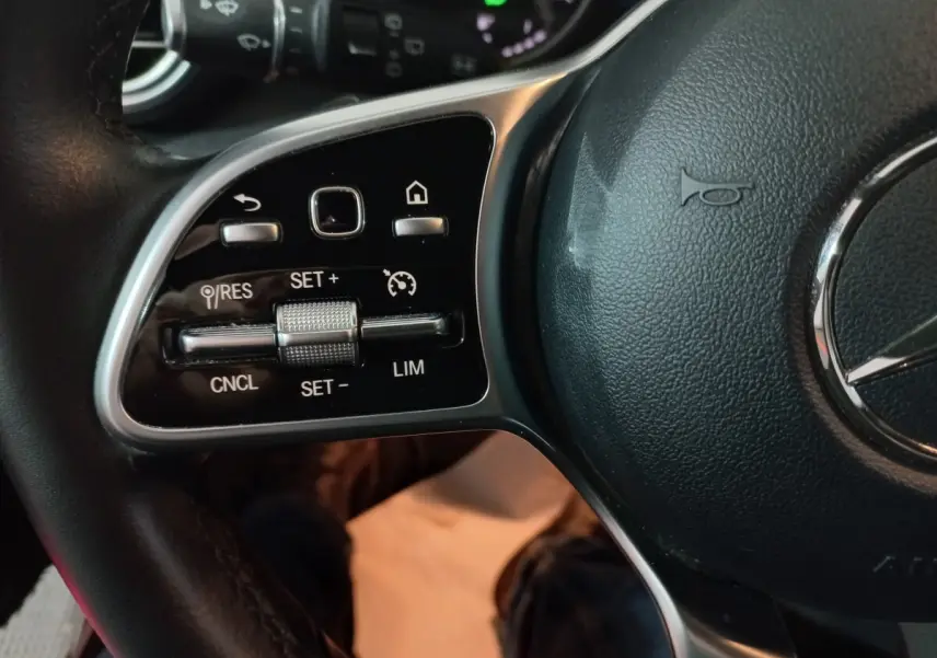 Gros plan sur les commandes du volant côté gauche du Mercedes GLC 300 E Business Line 2021, cuir noir.