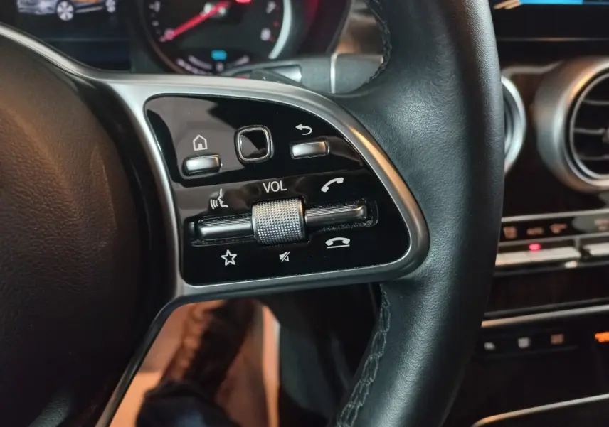 Gros plan sur les commandes du volant côté gauche du Mercedes GLC 300 E Business Line noir, tableau de bord en arrière-plan.