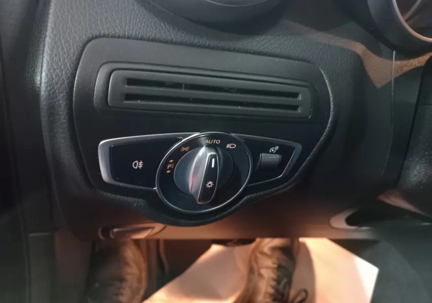 Gros plan sur la commande d'éclairage noire et chrome côté gauche du tableau de bord du Mercedes GLC 300 E noir.