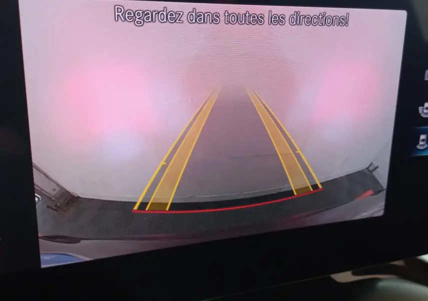 Vue caméra de recul du Mercedes GLC 300 E Business Line noir montrant les lignes de guidage jaunes et le pare-chocs arrière.