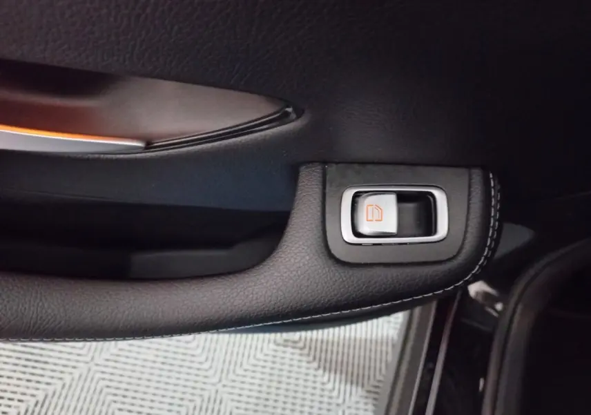 Gros plan sur la poignée intérieure noire avec bouton de déverrouillage orange du côté gauche d'un Mercedes GLC 300 E Business Line 2021.
