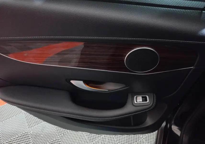 Gros plan sur la garniture intérieure noire et bois foncé de la porte côté gauche du Mercedes GLC 300 E Business Line 2021.