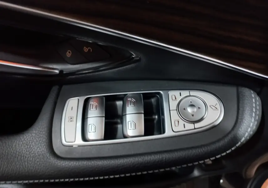 Gros plan sur les commandes de lève-vitres et rétroviseurs côté gauche d'une Mercedes GLC noire, finition Business Line.