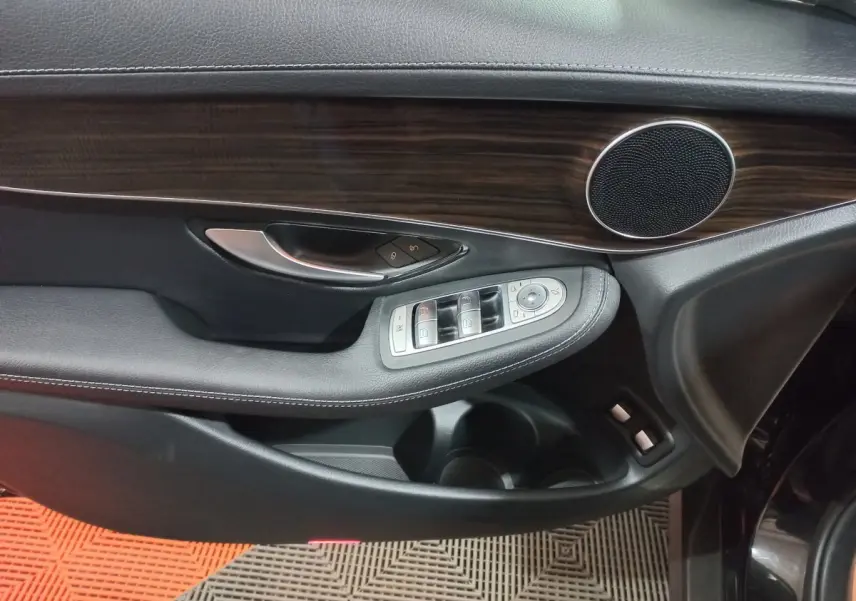 Détail de la porte côté gauche noire du Mercedes GLC 300 E avec insert bois et commandes de vitres et rétroviseurs.