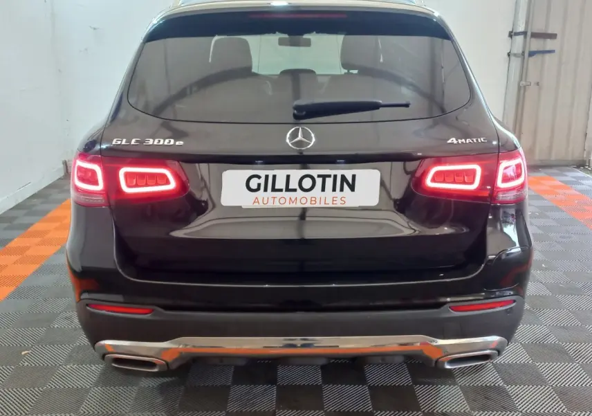 Vue arrière d'un Mercedes GLC 300e noir avec feux LED allumés et logo 4MATIC visible en intérieur.