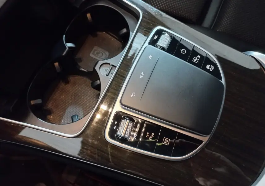 Gros plan sur la console centrale en bois foncé avec pavé tactile et commandes du Mercedes GLC noir 2021 hybride rechargeable.