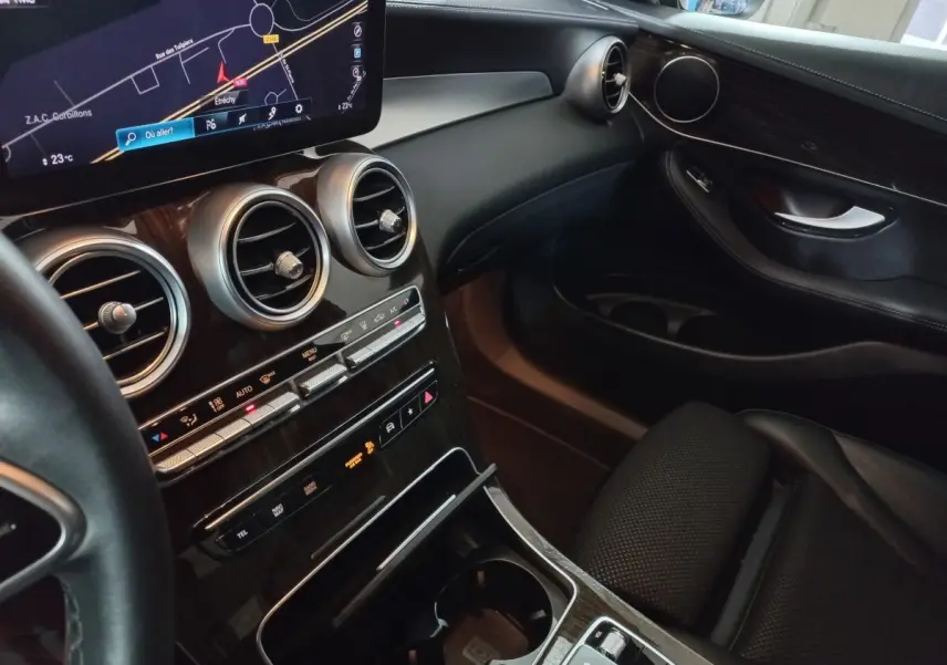 Vue intérieure côté passager du tableau de bord et console centrale en bois noir du Mercedes GLC 300 E Business Line 2021.