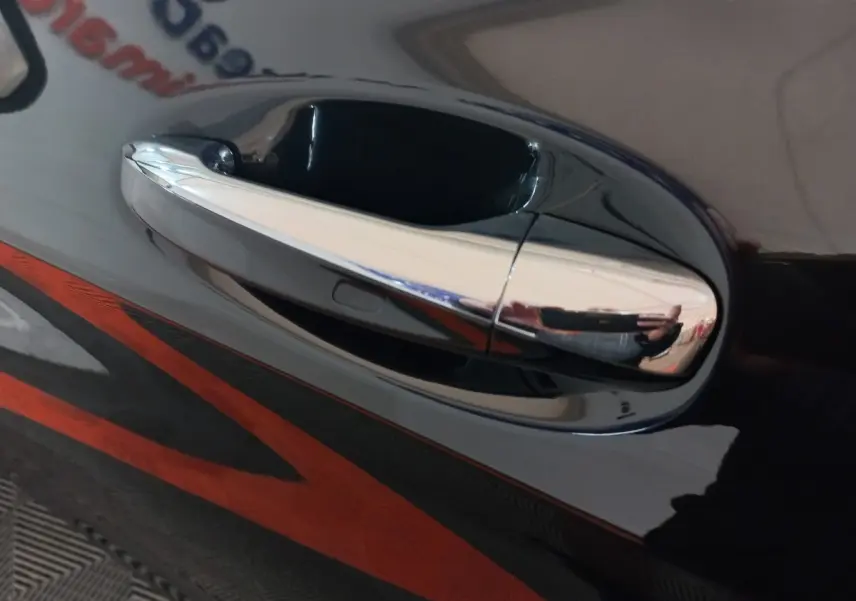 Poignée de porte chromée en gros plan sur la portière noire d'un Mercedes GLC 300 E Business Line 4MATIC hybride rechargeable.