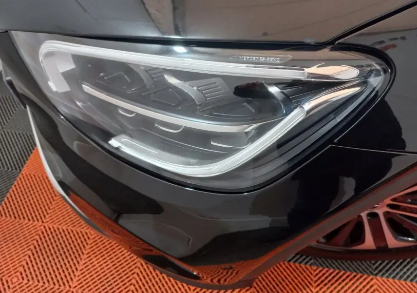 Gros plan sur le phare avant droit noir brillant du Mercedes GLC 300 E Business Line hybride rechargeable.