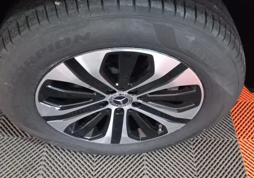 Gros plan sur la roue avant d'un Mercedes GLC 300 E noir avec jante alliage bicolore et logo étoile central