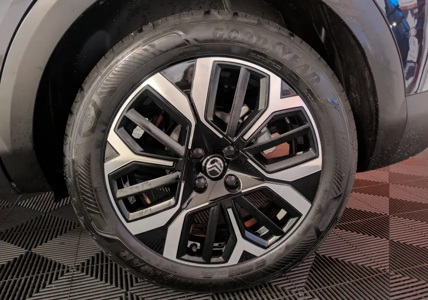 Gros plan sur la jante alliage 18 pouces bicolore du côté avant droit d'une Citroën C4 bleu nuit hybride 2025.