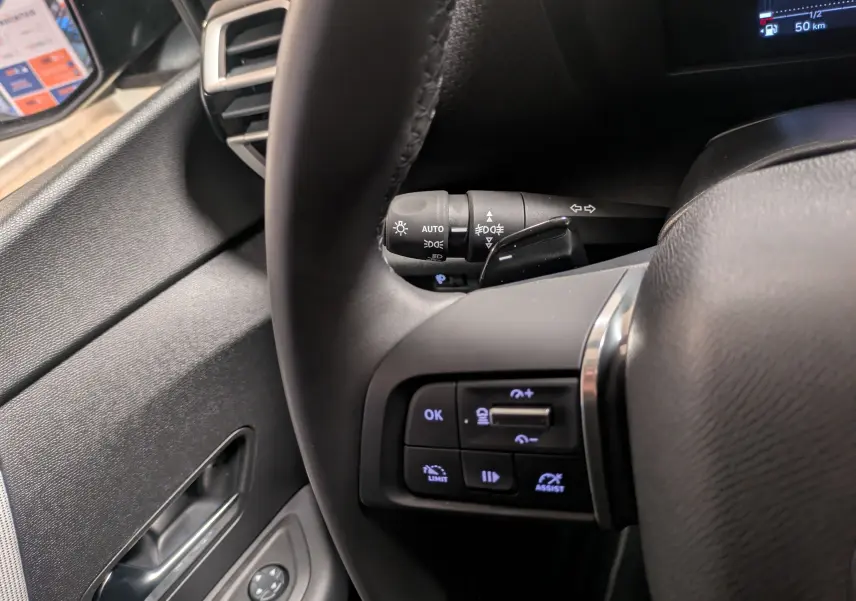 Gros plan sur le volant côté gauche de la Citroën C4 hybride 2025, avec commandes intégrées et levier de clignotant visible.