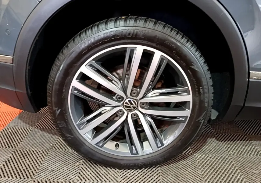 Gros plan sur la roue avant droite du Volkswagen Tiguan gris clair, jante alliage à multiples branches et pneu Bridgestone.