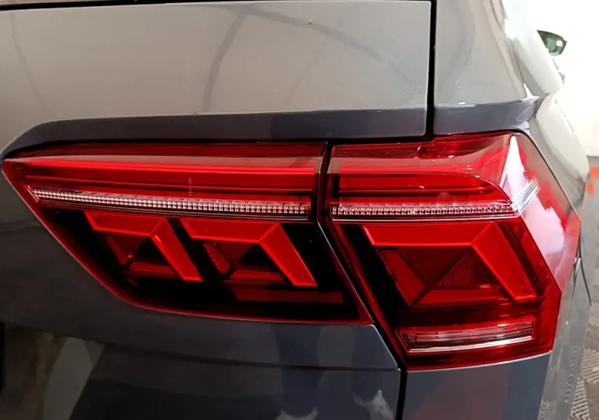Gros plan sur le feu arrière droit rouge d’un Volkswagen Tiguan gris clair, soulignant ses formes géométriques modernes.