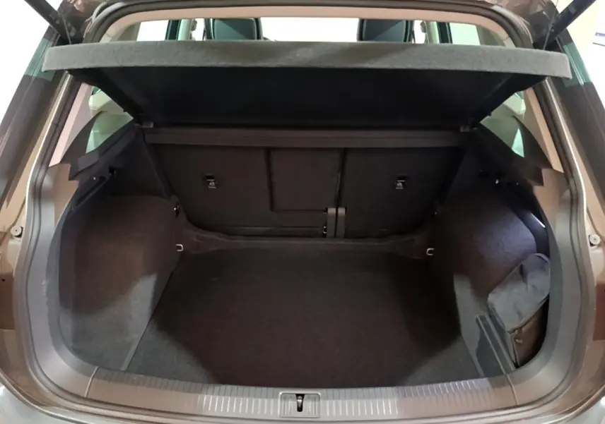 Coffre ouvert du Volkswagen Tiguan gris clair 2022, vue arrière montrant l’espace de chargement vide et la tablette de couverture.