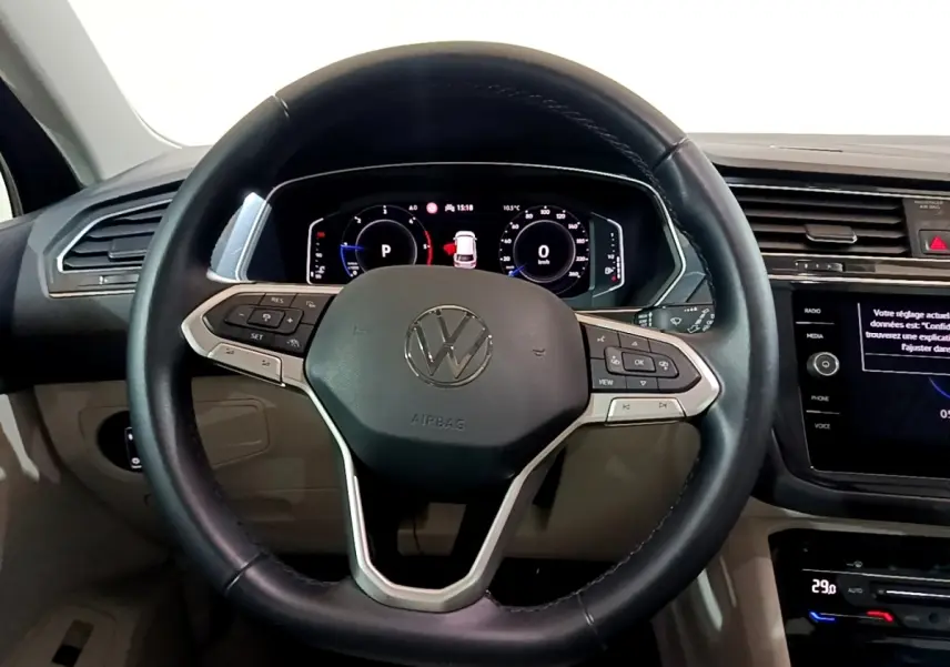 Vue intérieure centrée sur le volant cuir noir et le tableau de bord numérique du Volkswagen Tiguan 2022.