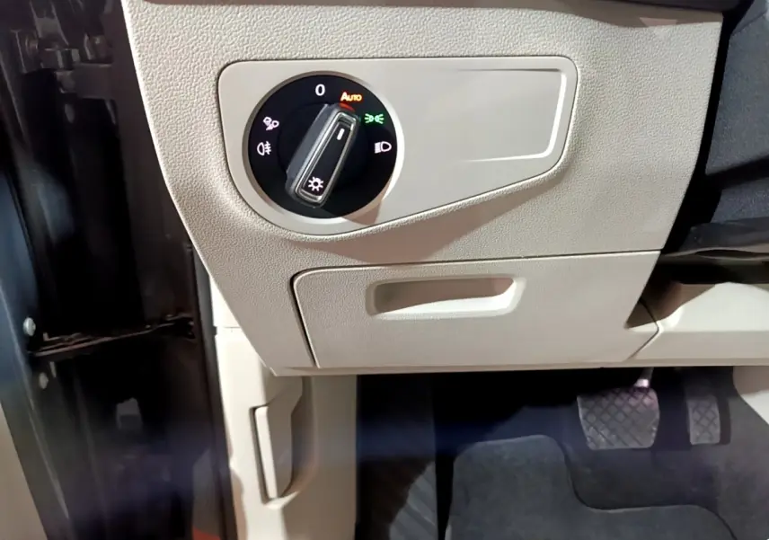 Gros plan sur le bouton de commande des phares dans l’habitacle beige du Volkswagen Tiguan 2.0 TDI 2022.