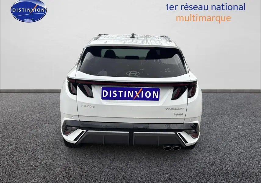 Vue arrière d'un Hyundai Tucson blanc sérénité hybride avec feux LED et double sortie d'échappement à droite.