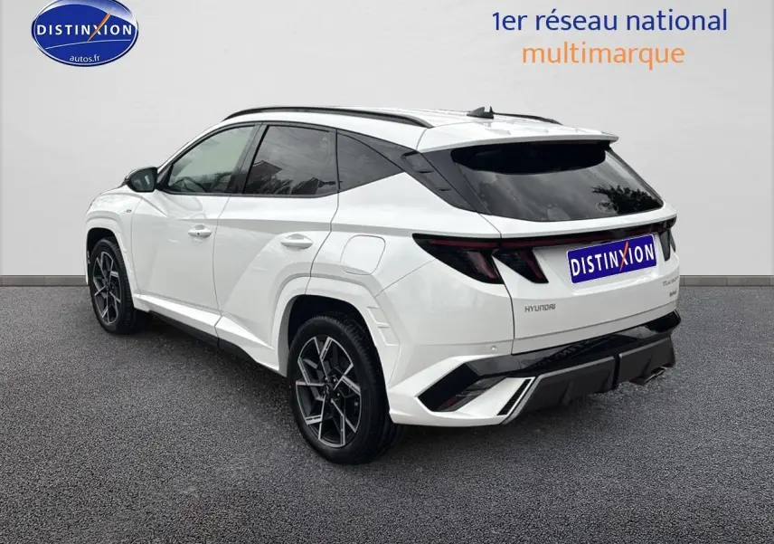 Vue 3/4 arrière droite d'un Hyundai Tucson blanc sérénité avec jantes alliage 19 et détails noirs N Line.