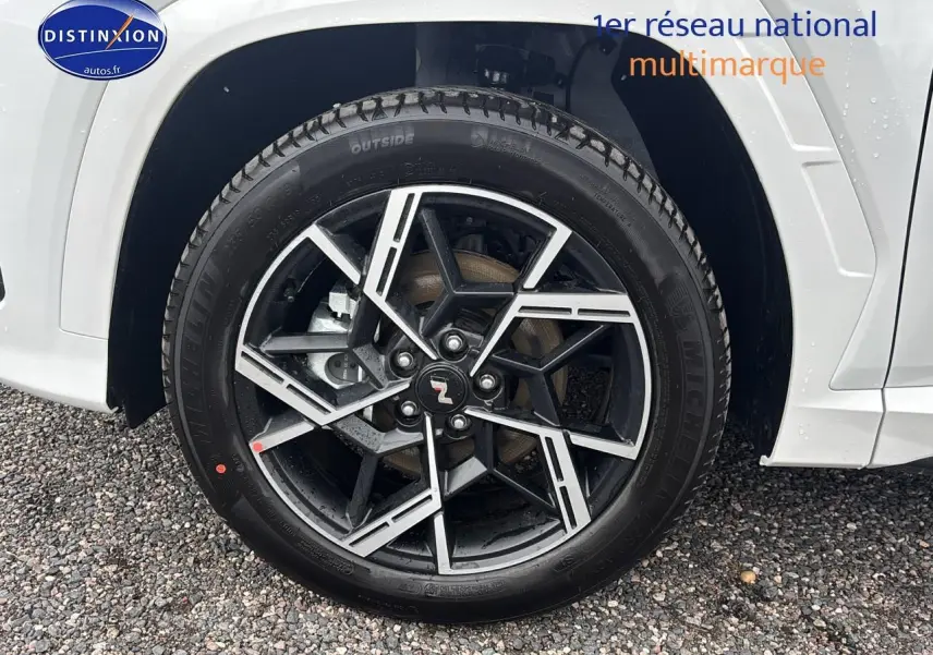 Gros plan sur la jante alliage 19 pouces noire et argent du côté gauche d’un Hyundai Tucson blanc sérénité.