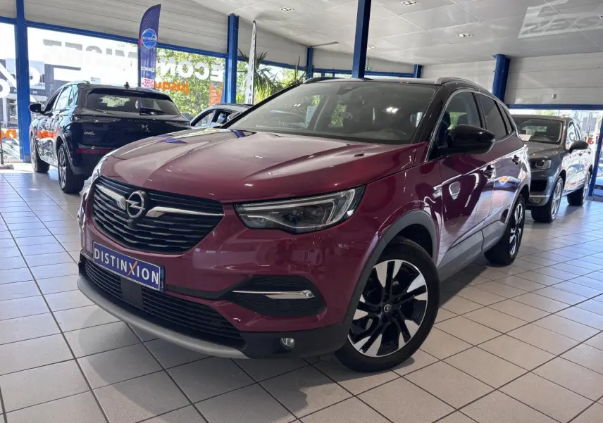 Opel Grandland rouge foncé en 3/4 avant droit, avec jantes alliage noires et toit noir en concession.
