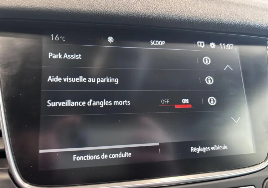 Écran tactile intérieur de l’Opel Grandland rouge foncé affichant les options d’aide au stationnement et surveillance d’angles morts.