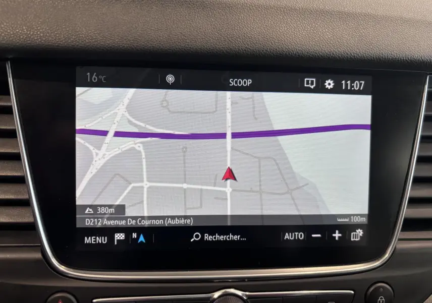 Écran tactile du système de navigation intégré dans le tableau de bord de l'Opel Grandland rouge foncé.