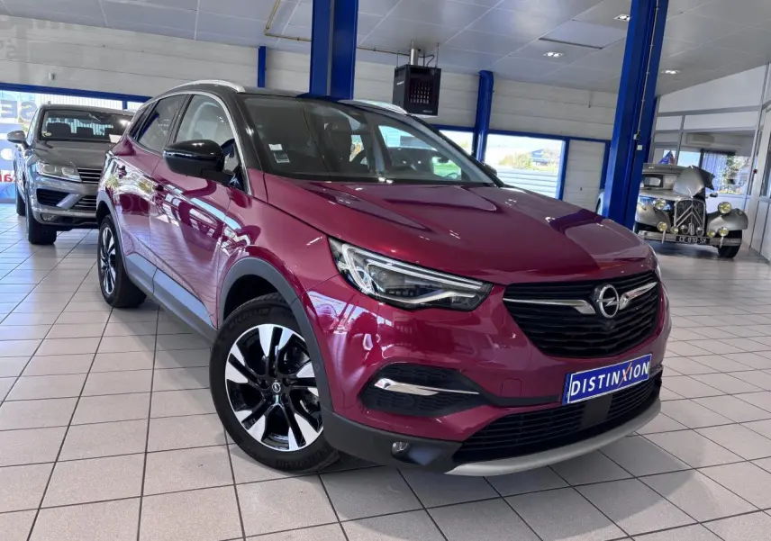 Opel Grandland rouge foncé en 3/4 avant droit, avec jantes alliage noires et toit noir en showroom.