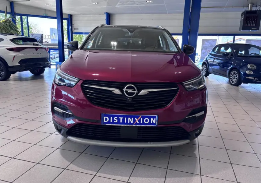 Vue de face d'un Opel Grandland rouge foncé avec calandre noire et détails chromés, en showroom lumineux.