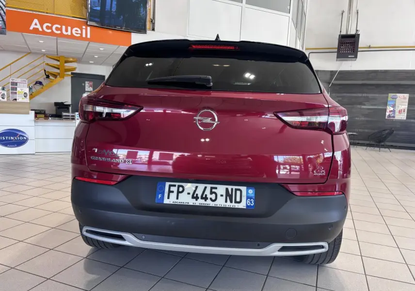 Vue arrière d'un Opel Grandland X rouge foncé avec hayon motorisé et feux arrière LED dans un showroom.