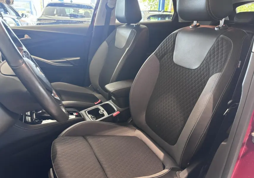 Vue intérieure côté avant droit de l'Opel Grandland rouge foncé, montrant les sièges avant en tissu noir et gris.