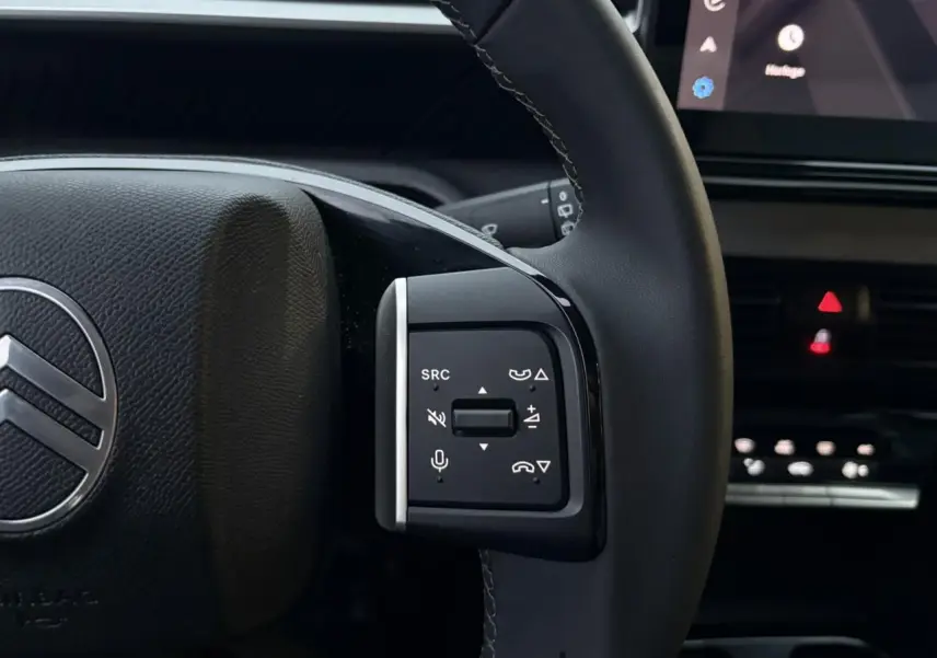 Gros plan sur le volant côté gauche de la Citroën C3 2025, avec commandes audio et micro intégrées, intérieur noir.