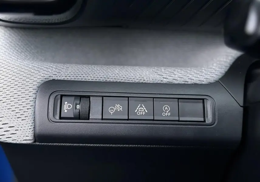 Gros plan sur les commandes de sécurité et d’éclairage côté gauche du tableau de bord de la Citroën C3 Bright Blue 2025.