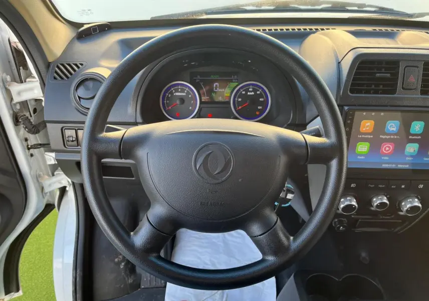 Vue intérieure centrée sur le volant noir du Seres DFSK EC35 électrique blanc avec tableau de bord et écran tactile.