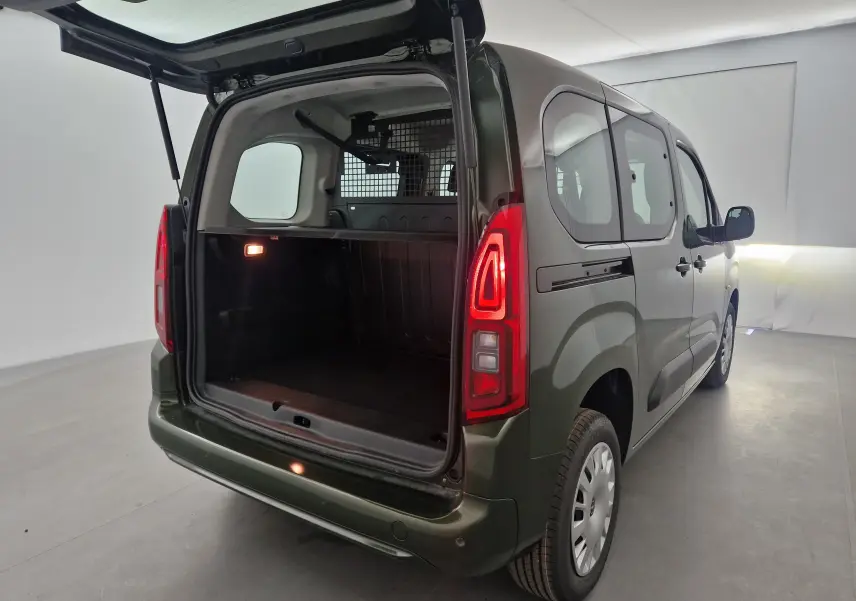 Vue 3/4 arrière droite d'un Opel Combo Life vert Sirkka avec hayon ouvert et grille de séparation visible dans le coffre.