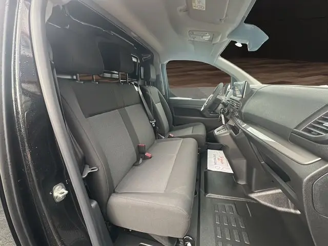 Intérieur du Citroën Jumpy noir 2025, vue latérale côté conducteur, sièges tissu noir et tableau de bord moderne.